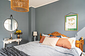 Bedroom with blue-grey wall, wooden bed and rattan lampshade