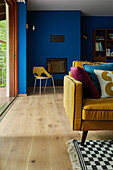 Living room with blue walls, yellow sofa and patterned carpet