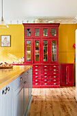 Roter Vitrinenschrank in Landhausküche mit gelber Wand