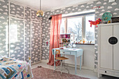 Children's room with cloud pattern wallpaper and colourful decorative elements