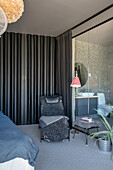 Dark bedroom with black curtains and glass room divider, adjoining bathroom