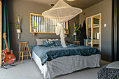 Bedroom with mosquito net, grey walls and guitar