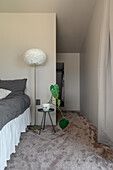 Minimalist bedroom with floor lamp and green plant