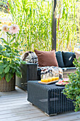 Rattan seating area on terrace with cushions, blanket and orange juice