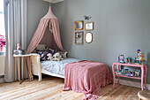 Children's room with canopy, toys and wooden floorboards