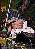 Deckchair with blanket and cushion next to rake and thermos flask