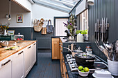 Moderne Küche mit Kochinsel, graublauer Wandvertäfelung und Messerleiste