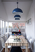 Bright dining area with white wood panelling and blue pendant lights