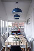 Dining area on sun porch white wood paneling and blue pendant lights