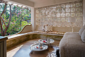 Sitzbereich mit ornamentaler Betonwand und Metalltischen mit Blick in Garten