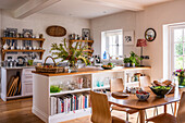 Country kitchen with wooden table, open shelves and wildflowers in a vase