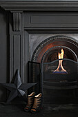 Highheels and black star in front of open fireplace with fire