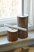 Candle holder made from wooden logs on a windowsill with a view outside