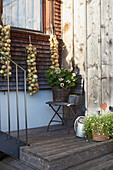 Terrassenbereich mit Holzstufen, Gartenstuhl und dekorativen Pflanzen