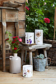 Garden decoration made of lanterns with dried flowers, vase with flowers, wooden stool and succulent plant