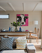 Dining table with wooden chairs and modern cow portrait in the bright living room