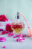 A shaking lotion (oil and hydrolate) in a bottle with a spray pump surrounded by rose petals