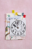 Karten mit Notizen und einegedruckte Uhr auf rosa Untergrund (Konzentration)