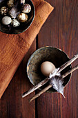 Bowl with an egg, wooden sticks, and a feather as an Easter decoration