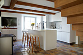 White kitchen counter with bar stools in light-colored kitchen