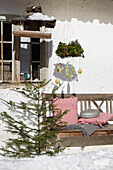 Rustic wooden bench with checkered cushions and winter decoration in the snow