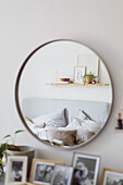 Round wall mirror in the bedroom, with black and white photo collection underneath