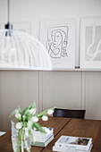 Books and white tulips on a wooden table, drawings on a narrow shelf