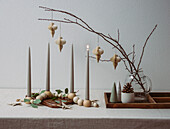 Candles, wooden beads and twigs with paper Christmas decorations