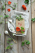 Place cards with stamped initials, with poppy blossoms and poppy pods on place setting