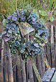Hydrangea wreath made with grass and smoke tree hanging on garden chair
