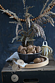 stoneware bowl with walnuts and dried grass with wooden bead necklace and lantern made of golden paper