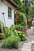 Garden path with stone slabs and flowering perennials next to a house