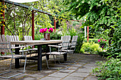 Terrasse mit Gartenmöbeln und Blumenarrangement im Sommer