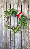 Christmas wreath on wooden wall with red ribbon and fir greenery