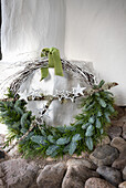 Christmas wreath with fir branches and stars on a white wall