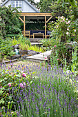 Blühender Lavendel im Garten, im Hintergrund überdachte Holzterrasse