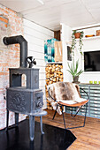 Old wood-burning stove next to metal chair with fur and apothecary cabinet in the living room