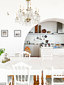 White dining table with chairs in classically designed dining area with chandelier