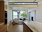 Contemporary kitchen with wooden fronts and kitchen island, with a seating area in the background