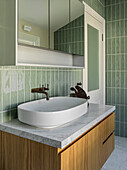 Washstand with countertop basin and in the bathroom with green tiles