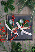 Silberlöffelchen mit Ilexsträußchen und Weihnachtsband auf Holztablett