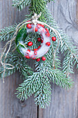 Spruce branch with wreath of ice with holly berries as door decoration
