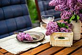 A spring place setting decorated with lilac flowers on a table outside