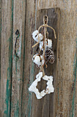 Garland with star of cotton and whitewashed cones hanging on old cupboard door