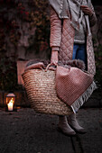 Person holding basket bag with blankets on terrace