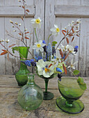 Grüne Glasware mit Gesteck aus Frühlingsblumen