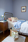 Messingbett und altes Nachtschränkchen im Gästezimmer mit blauen Wänden