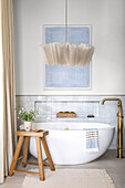 Oval, free-standing bathtub in front of partially tiled wall