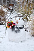 Snowman with a bouquet of tulips in the garden