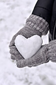 Gloved hands holding a snow heart
